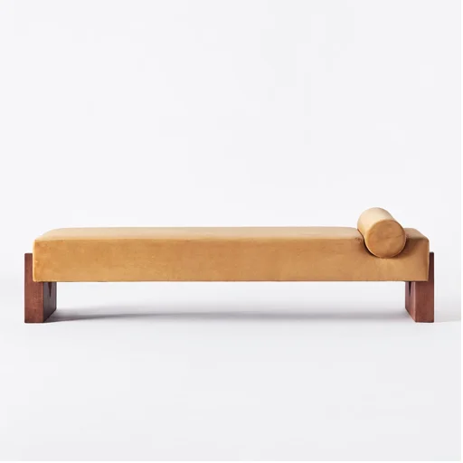A beige cushioned bench with a cylindrical pillow on one end, against a white background.