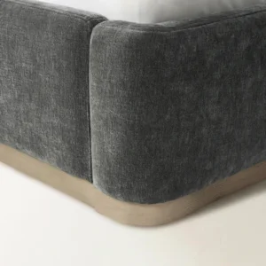 Dark grey upholstered bed with tall curved headboard, white bedding, and minimalist platform base.